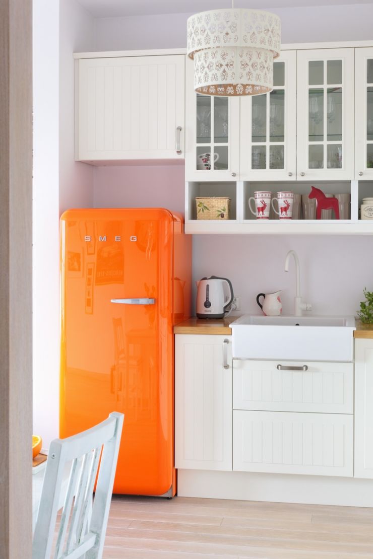 Orange retro fridge providing splash of colour in white, country-house kitchen